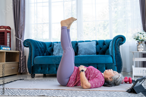 Portrait healthy senior woman exercise with lying leg lift photo