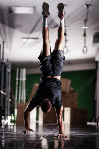 Muscular athlete standing and walking on hands upside down