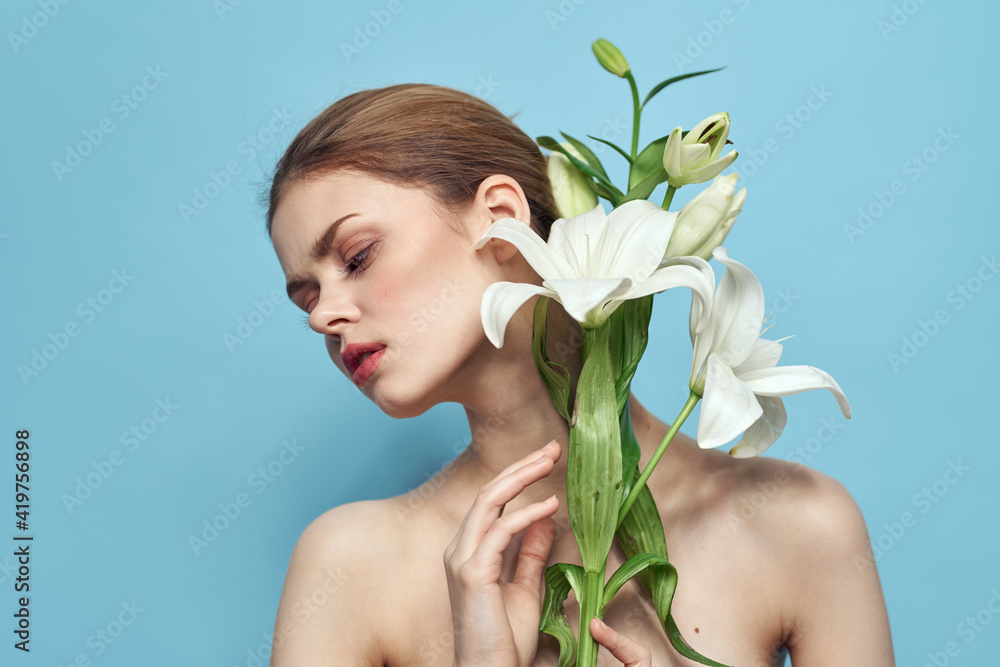 Beautiful girl with a bouquet of white flowers on a blue background cropped view naked shoulders portrait Beautiful girl with a bouquet of white flowers on a blue background cropped view naked shoulders portrait