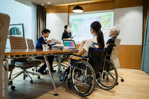 車椅子に乗った女性が会議に参加している © Monet