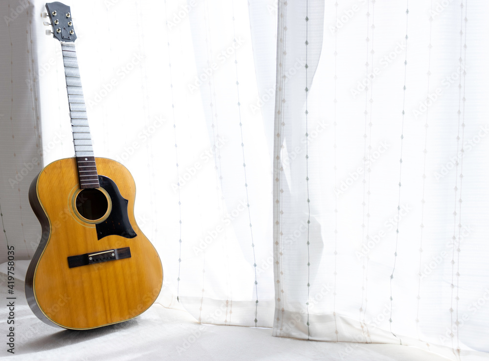 Obraz premium 窓際に立てかけたメンテナンス中のアコースティックギター。