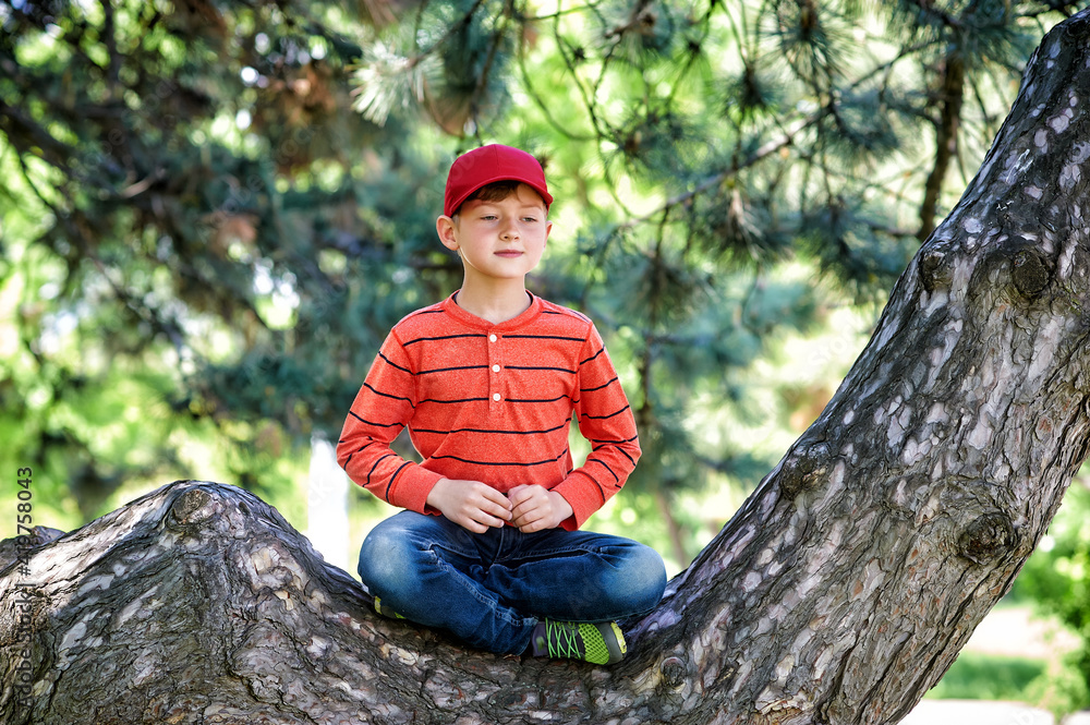 Happy boy sitting on a tree in the lotus position