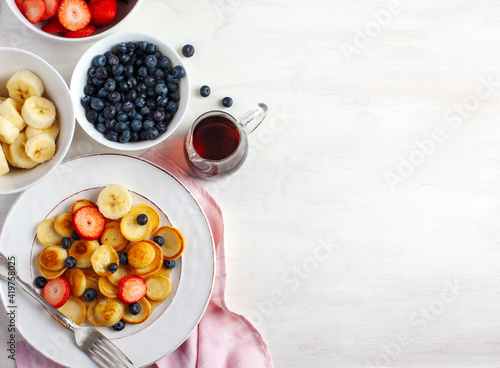 Breakfast with tiny pancakes and berries, copy space