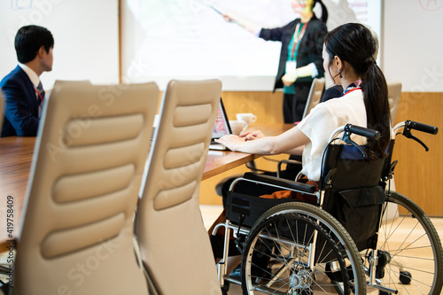 車椅子の女性社員が会議に参加している