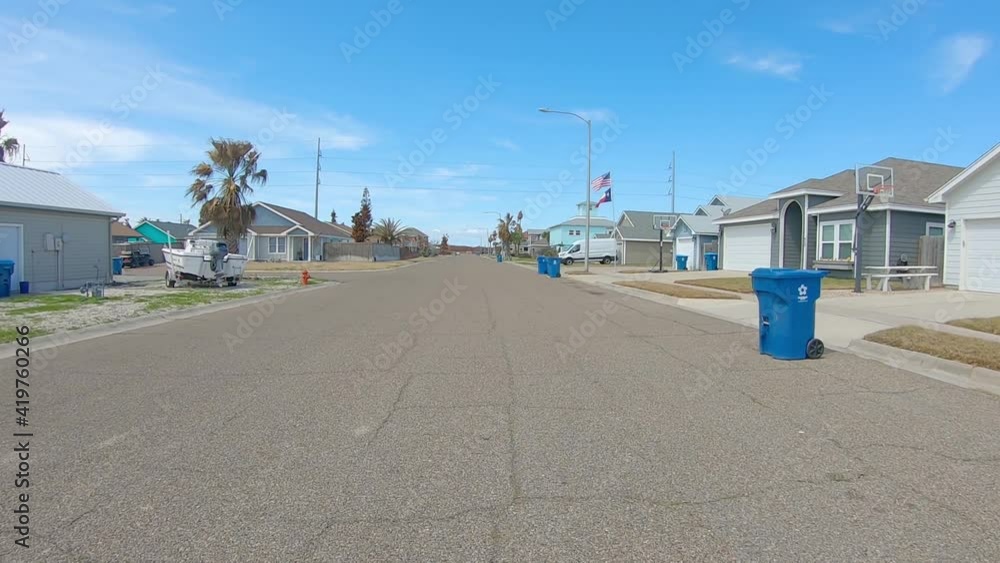 POV while driving thru a neighborhood of mostly vacation homes and fenced yards on a beautiful day in Port Aransas, Texas on Mustang Island; point of view POV while driving thru a neighborhood of mostly vacation homes and fenced yards on a beautiful day in Port Aransas, Texas on Mustang Island; point of view