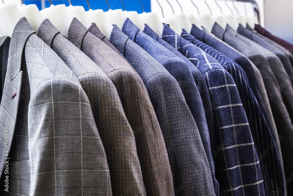 Fototapeta premium men's jackets in check and stripes hang on hangers in the atelier