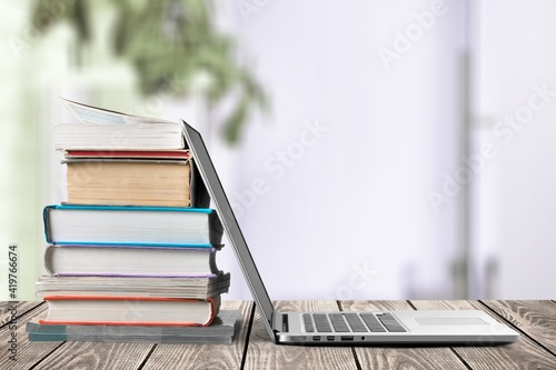 Stack of books with modern laptop on table © BillionPhotos.com