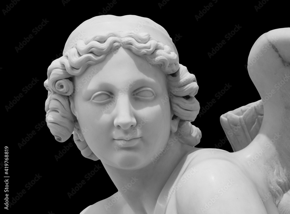 Ancient white marble sculpture head of angel. Antique statue isolated on black background. A carved marble cemetery memorial angel Ancient white marble sculpture head of angel. Antique statue isolated on black background. A carved marble cemetery memorial angel
