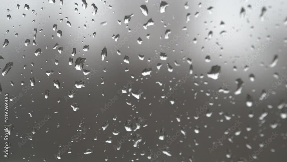 Rain drops land on a window and trickle down the glass during a rain storm. Rain drops land on a window and trickle down the glass during a rain storm.