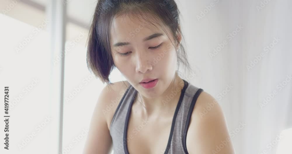 Face close up Asian woman lift dumbbell up for bicep muscle workout weight training exercise at home in sportswear. Take care health in quarantine coronavirus with new normal social distancing Face close up Asian woman lift dumbbell up for bicep muscle workout weight training exercise at home in sportswear. Take care health in quarantine coronavirus with new normal social distancing