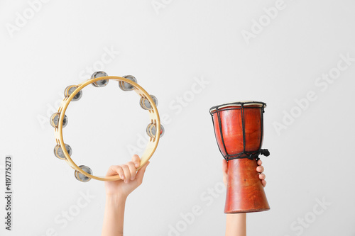 Fototapeta Woman holding tambourine and djembe on light background