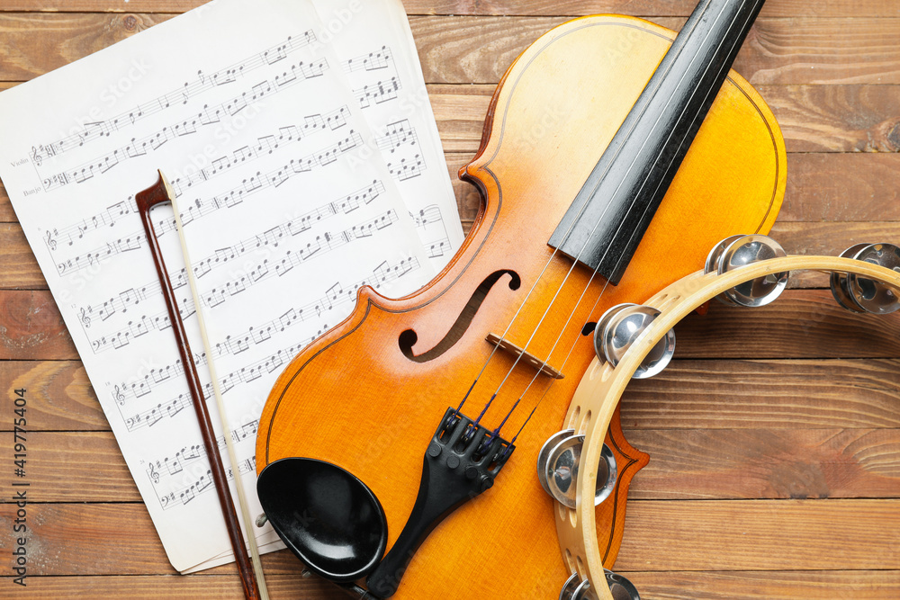 Fototapeta premium Violin, tambourine and music notes on wooden background