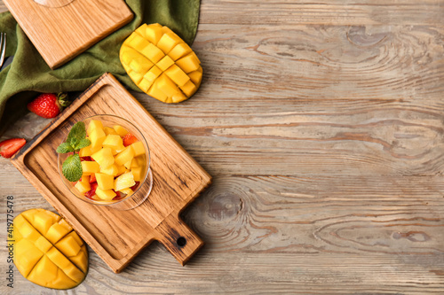 Glass bowl with tropical fruit salad on wooden background