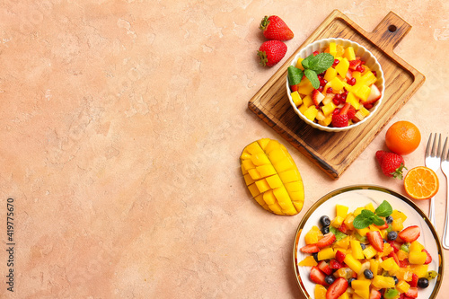 Bowl and plate with tropical fruit salad on color background © Pixel-Shot