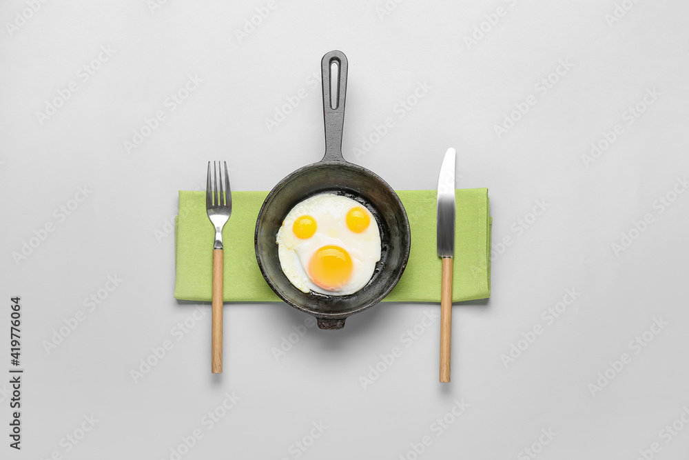 Frying pan with tasty eggs on light background Frying pan with tasty eggs on light background