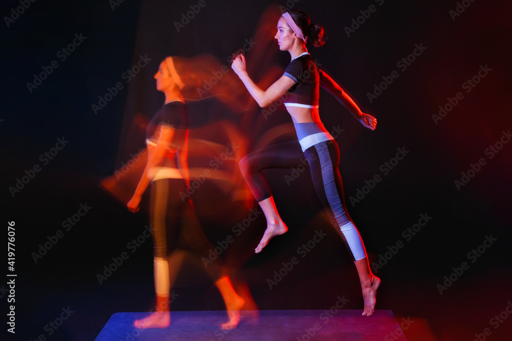One woman doing fitness exercises isolated on a black background with a light painting effect. Mixed light.