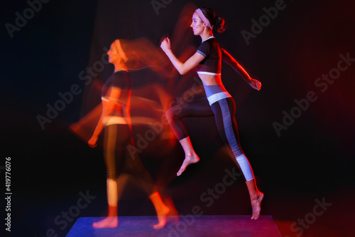 One woman doing fitness exercises isolated on a black background with a light painting effect. Mixed light.