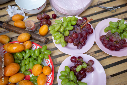 Fruits in green grapes and purple plates look delicious and have Sweet Yellow Marian Plum. photo