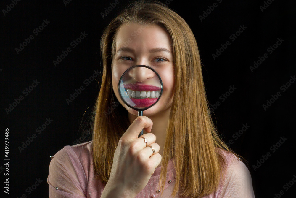 Young beautiful woman , enlarges lips and teeth with a magnifying glass Young beautiful woman , enlarges lips and teeth with a magnifying glass