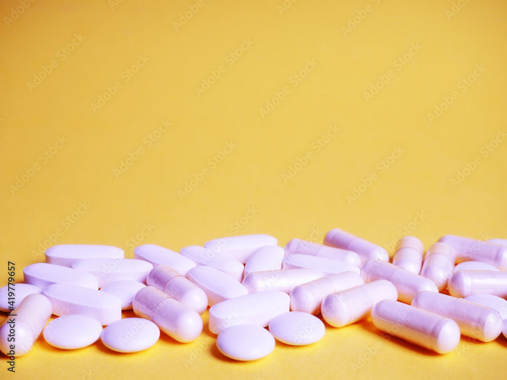 a lot of different white tablets on a yellow background, the concept of health and medicine a lot of different white tablets on a yellow background, the concept of health and medicine