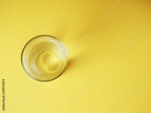 minimalistic concept of water consumption, one glass of water on a yellow background