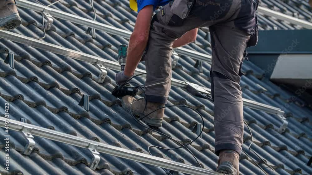 Worker Attaches Wire Box to Solar Panel Railing Mounts on Roof Worker Attaches Wire Box to Solar Panel Railing Mounts on Roof