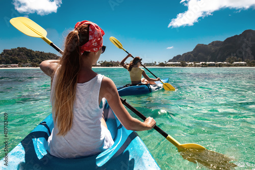 Two girls walks by sea kayaks or canoes