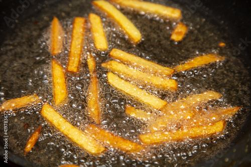 French fries are fried in oil in a pan. © schankz