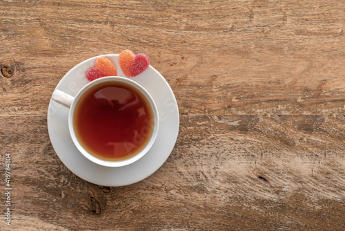 Tea break concept. Tea cup, marmalade in the form of heart on wooden table with copy space.