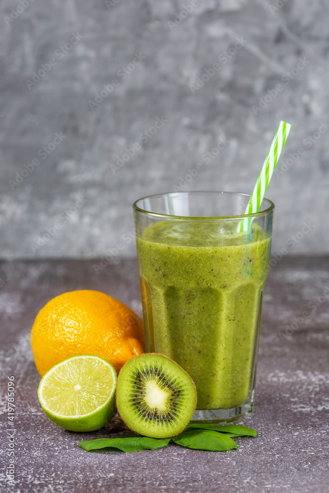 Fresh healthy smoothie drink in a tall glass glass with fruits on gray