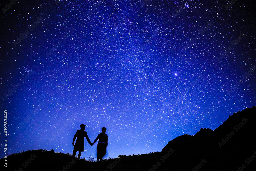 Silhouette of  couple on the hill.  Stargazing at Oahu island, Hawaii. Starry night sky, Milky Way galaxy astrophotography.