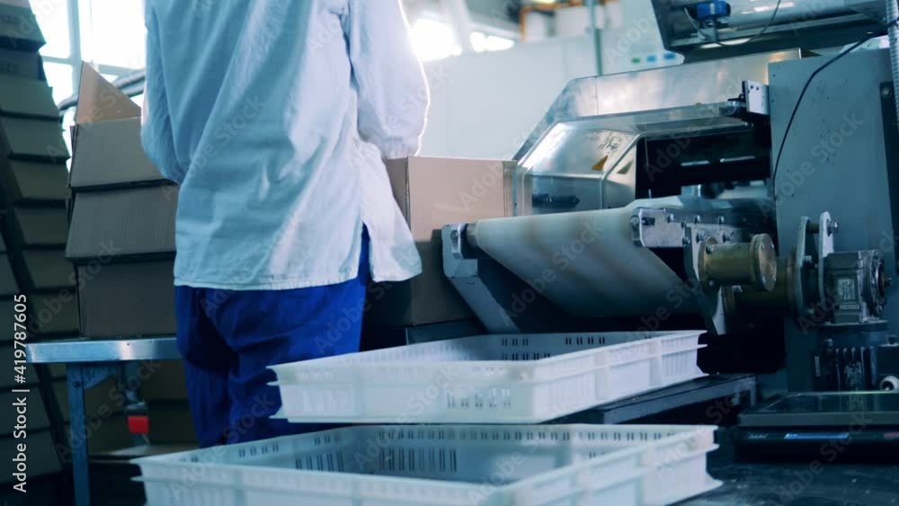 Female factory worker is putting white packages into boxes Female factory worker is putting white packages into boxes