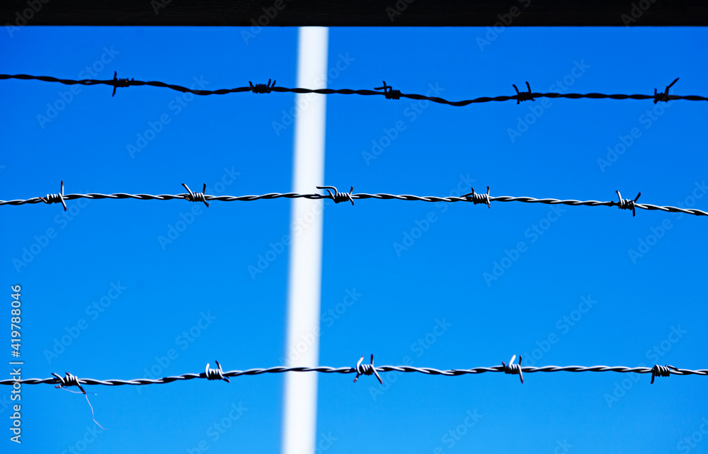 three lines of barbed wire against a blue background three lines of barbed wire against a blue background