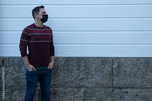 young man with mask on the street with white blind on background © tetxu
