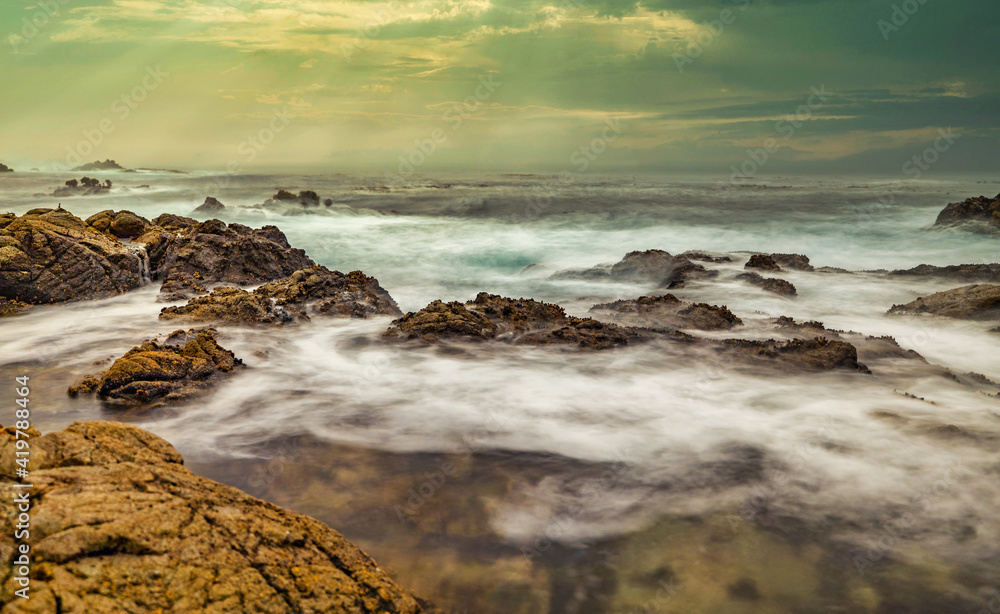 Beautiful seascape, ocean views, rocky coast, sunlight on the horizon. Composition of nature. Sunset scenery background. Cloudy sky. Water Reflection. California Seashore.