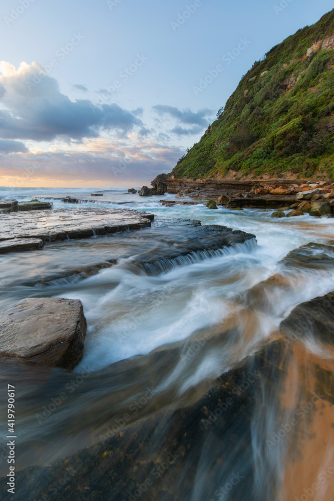 Sea water flowing around rock formation on the shore.