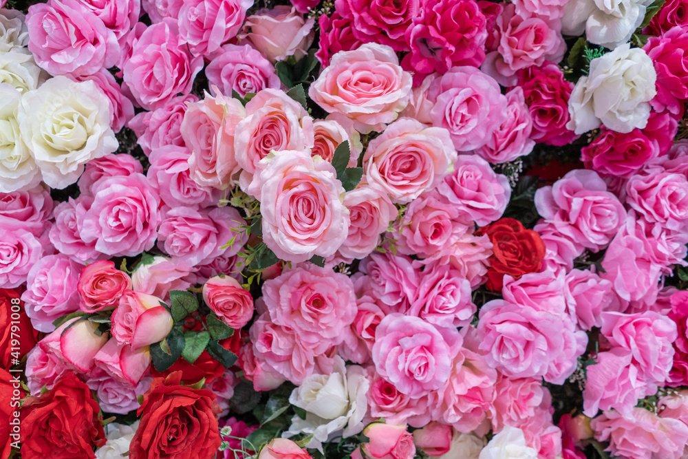 Background of artificial roses of different colors, pink reds white roses