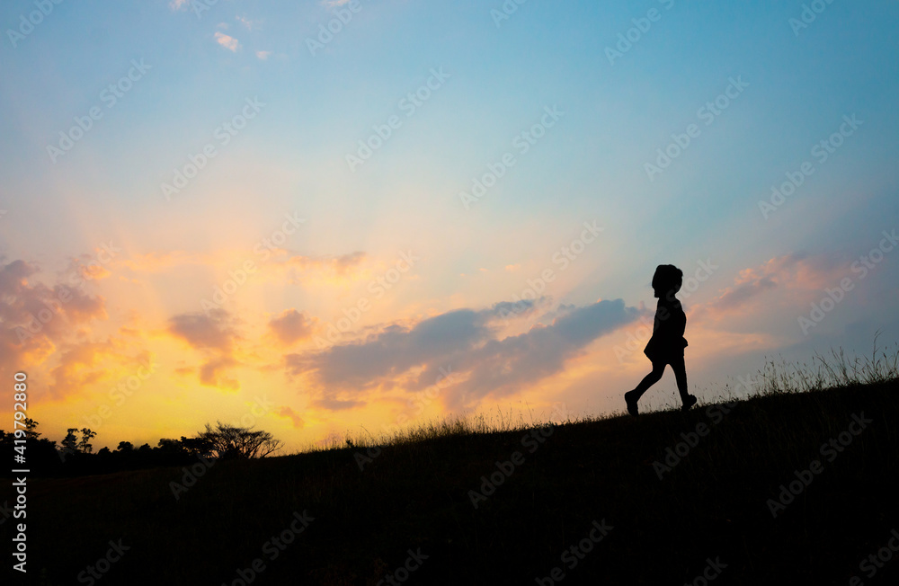 The silhouette of a girl running on the hill at sunset