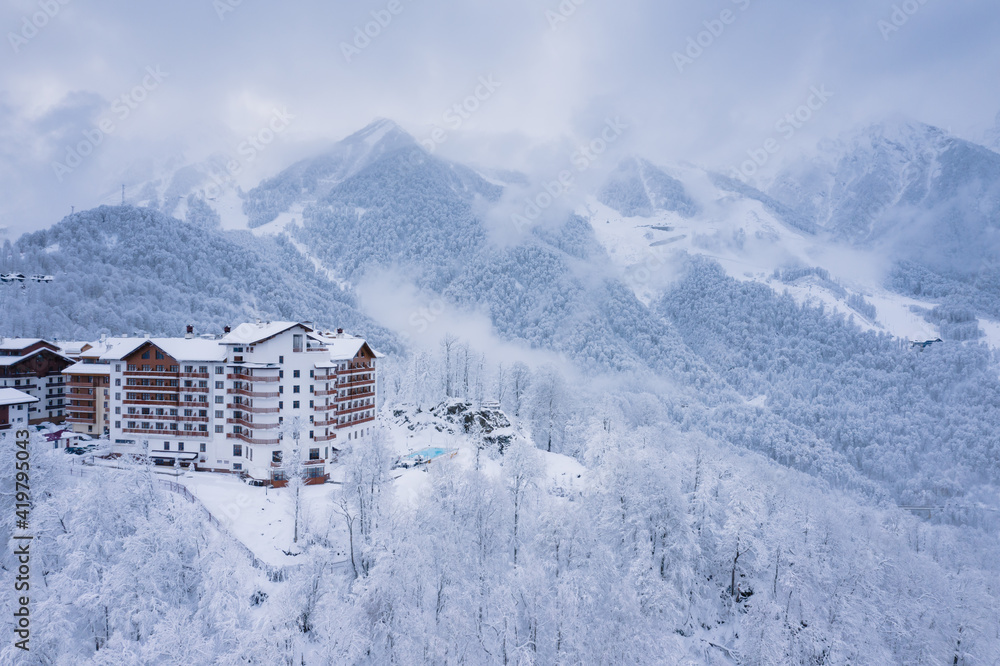 Winter aerial view of the Ski Resort Rosa Khutor. A complex of hotels on the site of the former Olympic village of Rosa Plateau at an altitude of 1170 m from sea level. Krasnaya Polyana, Sochi, Russia - obrazy, fototapety, plakaty 