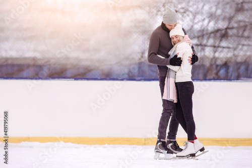 Happy Caucasian Couple in Winter Skating Outdoors and Standing Embraced with Positive Expression Over a Snowy Winter Landscape.