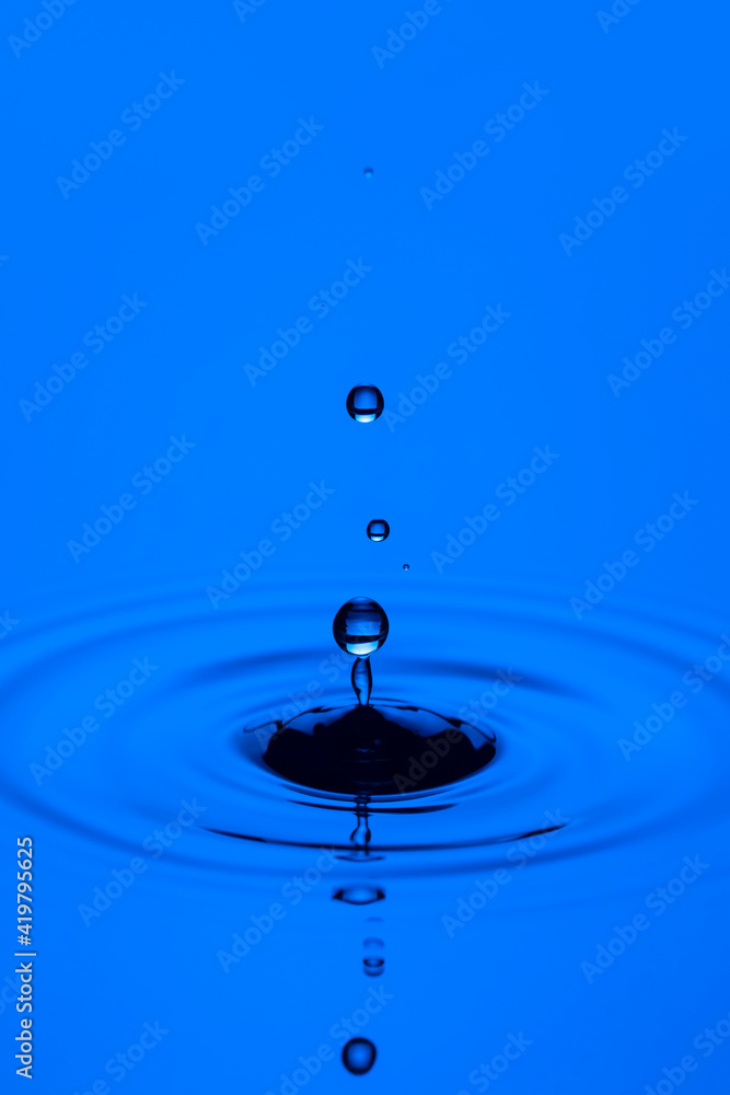 Abstract Macro Shot of Multiple Blue Water Droplets Over Tranquil Water Surface.