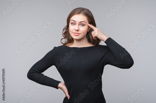 Portrait of a young woman thinking and pointing at her forehead. Half length portrait © AstiMak