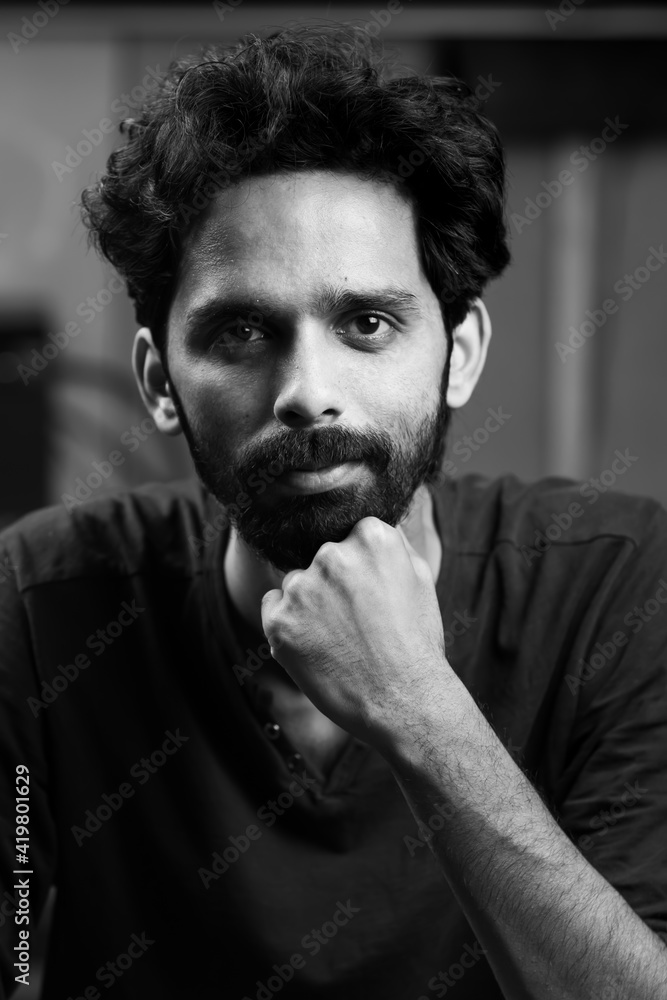 Young handsome Indian Asian male boy with black dense hair and beard posing  for grayscale photo