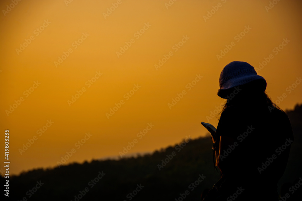 Woman standing to use smartphone backlit sun in the dawn, freestyle Woman standing to use smartphone backlit sun in the dawn, freestyle