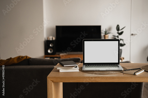 Laptop with blank copy space screen on table with notebooks on wooden table. Minimalist home office workspace. Mockup template. © Floral Deco