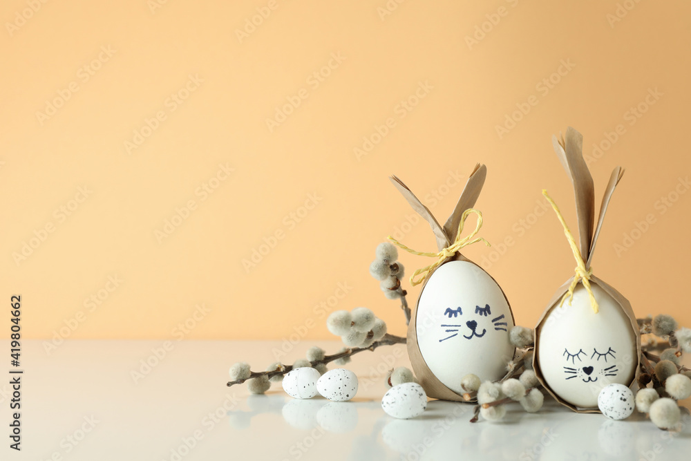 Easter bunnies made of eggs, quail eggs and catkins against beige background Easter bunnies made of eggs, quail eggs and catkins against beige background