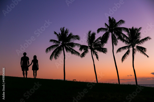 Couple next to palm trees  silhouette sunset   Kakaako Waterfront Park  Honolulu  Oahu  Hawaii 