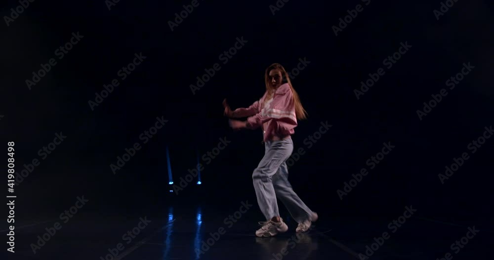 The camera captures an attractive and sexy young woman dancing incendiary on stage. She is in the dark, only flashes of light are visible behind her. She is wearing comfortable clothes The camera captures an attractive and sexy young woman dancing incendiary on stage. She is in the dark, only flashes of light are visible behind her. She is wearing comfortable clothes