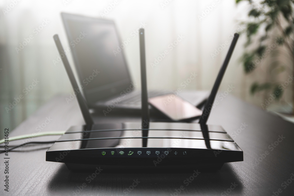 WIFI router connected to the internet on table and laptop in the background - obrazy, fototapety, plakaty 
