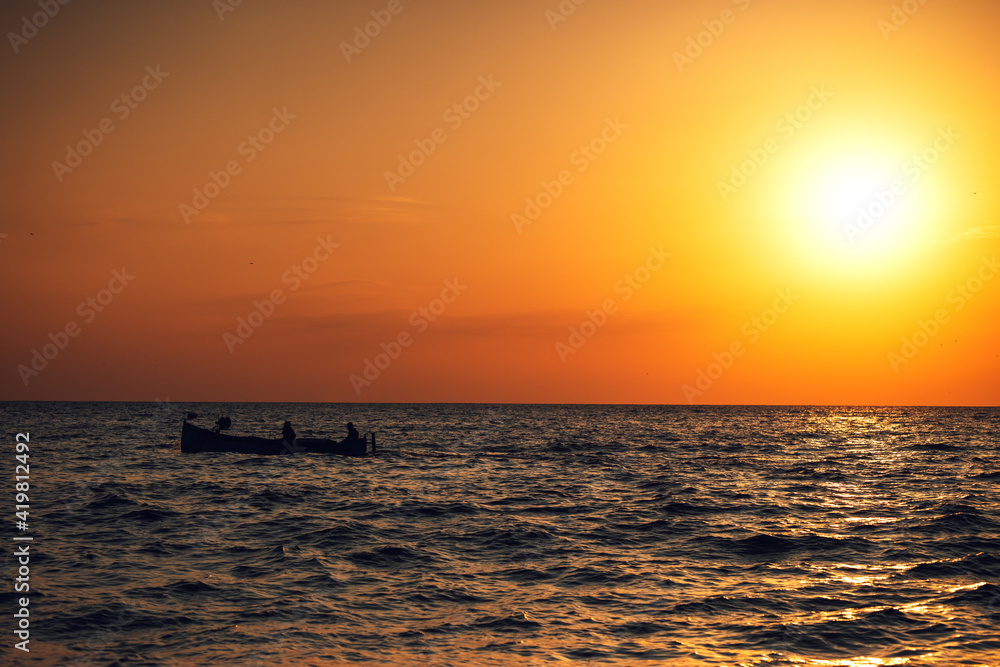 Fisherman sailling with his boat on beautiful sunrise over the sea
